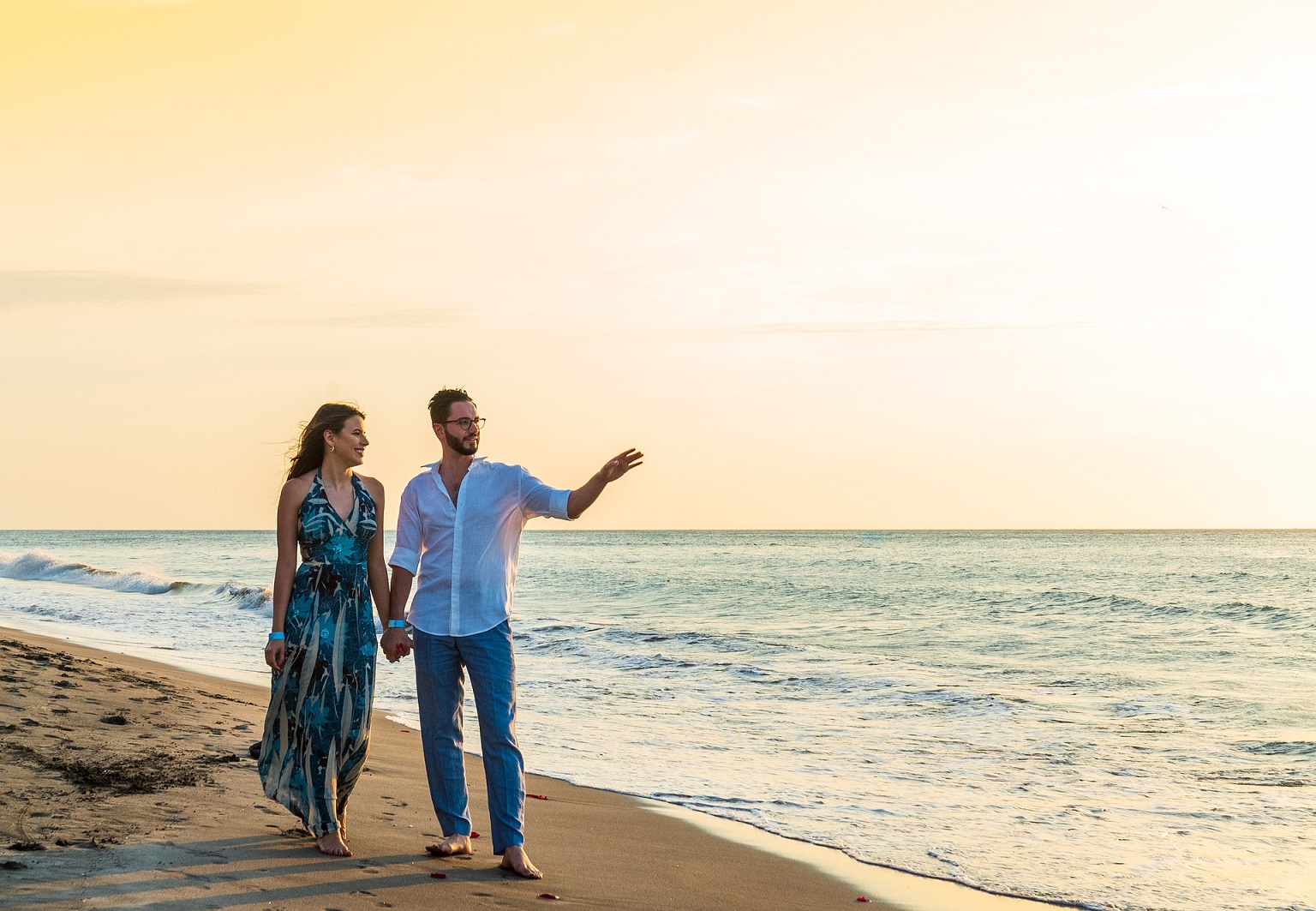 no-lazy nosso propósito é a sua liberdade financeira imagem de um casal jovem na beira do mar com roupas de festa apontando para a imensidão do mar