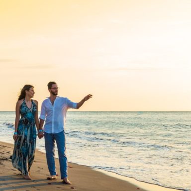 no-lazy nosso propósito é a sua liberdade financeira imagem de um casal jovem na beira do mar com roupas de festa apontando para a imensidão do mar